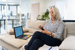© Luis Velasco/Stocksy - Mature Woman Reviewing Documents and Using Smartphone in Office Lounge
