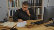 © Krakenimages.com - Young hispanic man in judge's robe working in office talking on phone and reviewing documents