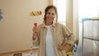 © Krakenimages.com - Woman smiling in new home interior, holding paint roller, suggesting a renovation project, with sunlight illuminating the room, capturing a moment of creativity and transformation.