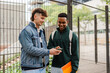 © Nuria Seguí/Stocksy - Smiling Male Student Showing Smart Phone To Friend