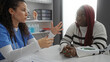 © Krakenimages.com - Female healthcare professional talking to african american woman patient in clinic indoors, emphasizing medical discussion and patient care in healthcare setting.