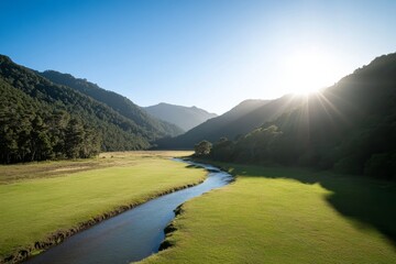 Aufkleber - A tranquil river meanders through a vibrant green valley, reflecting the bright blue sky, surrounded by trees and mountains, creating a peaceful natural landscape