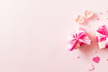 Wall Mural - Pink hearts and gift box with ribbon on a light pink background