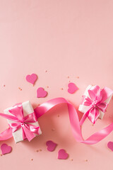 Wall Mural - Pink hearts and gift box with ribbon on a light pink background