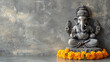 © Tropical studio - Hindu god Ganesha sculpture on grey background with copy space. Decorated for religious festival by orange flowers necklace and ceremonial offering. Travel background, Bali island art and culture.
