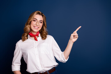 Wall Mural - Happy young woman in white shirt with red scarf pointing finger on dark blue background