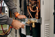 © Vadym - Technician's hands with tools working on the copper pipes of the air conditioner. The photo shows parts of the cooling system and connecting valves.