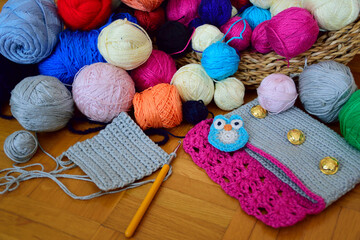 Colorful yarn balls in a basket, with crochet supplies, small crochet owl and crochet purse