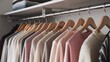 © Tom - A neat arrangement of women's clothing in various soft hues, hanging on wooden hangers in a stylish closet.