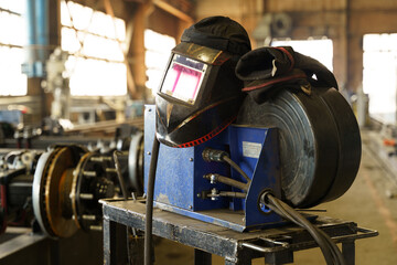 Poster - Welding equipment on a workshop table in a busy industrial setting