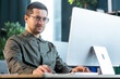 © Ivan - Confident young businessman working on computer at creative office