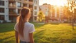 © HISTOCK - Young woman admiring residential buildings at sunset in a park