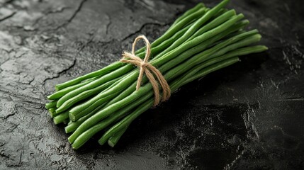 Canvas Print - A bundle of green beans tied together with twine on a textured black surface