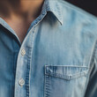 © ENRAM - Closeup of a light blue denim shirt photographed from the front focusing on the left side with a visible button row and part of the collar showing a portion of the n