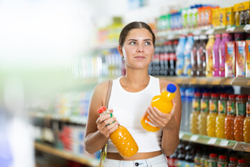 Wall Mural - Young woman shopper choosing soda in grocery store