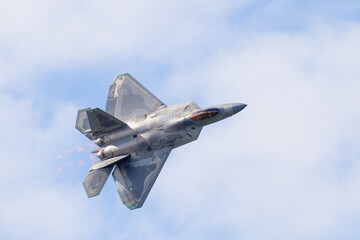 Wall Mural - Close top view of a F-22 Raptor in beautiful light in a turn, with afterburners on