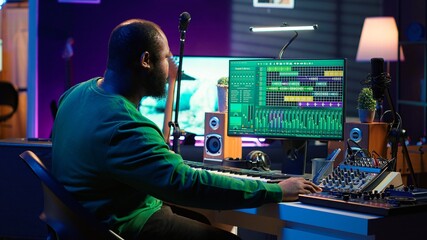 Leinwandbilder - Sound engineer pressing keys of electronic synthesizer and composing new song, adjusting volume levels on pre amp knobs. Composer producing music on piano midi controller, mixing tunes. Camera A.