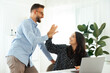 © Kateryna - Cheerful young man and woman sharing a high-five at a work desk, celebrating success during a collaborative project. Teamwork in the modern office, good job and results of multiracial colleagues