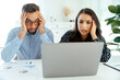 © Kateryna - Stressed multiracial man and woman puzzled looking at a laptop sitting in a modern workspace, reviewing critical business results, surrounded by paperwork and charts, showing worry and frustration