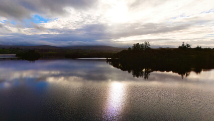 Wall Mural - Lough Eske in Donegal Ireland - A tranquil view of a lake reflecting the cloudy sky at dusk, showcasing natures peacefulness and serenity