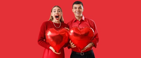 Wall Mural - Happy young couple with heart-shaped balloons on red background. Valentine's Day celebration