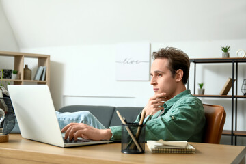 Male freelancer working with laptop at table in office