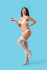 Wall Mural - Sexy young woman in underwear with gift box on blue background. Valentine's Day celebration