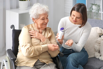 Sticker - Senior woman in wheelchair taking pills from nurse at home