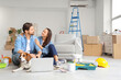 © Pixel-Shot - Young couple with Beagle dog and laptop during repair in their new house
