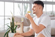 © Pixel-Shot - Sporty young man drinking lemon infused water at home