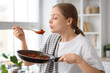 © Pixel-Shot - Young housewife blowing on fried food in kitchen
