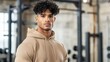 © mashimara - Focused Determination: A young man with a determined gaze, clad in a beige hoodie, exudes strength and confidence in this fitness-themed portrait.