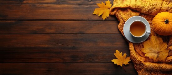 Wall Mural - Autumn still life with tea cup cozy small pumpkin and yellow maple leaves on wooden background flat lay top view seasonal decor