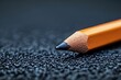 © natalia - A sharpened yellow pencil rests on a textured black surface.
