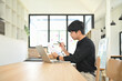 © Prathankarnpap - Young businessman reviewing report with charts and graphs while working on a laptop.