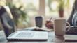 © sajida - person working on laptop, A home office setup with a laptop, notepad, coffee mug, and the professional focused on a virtual