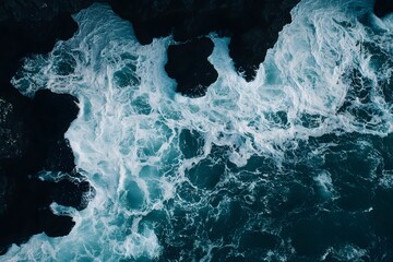 aerial view of ocean waves crashing on dark volcanic rocks, background texture