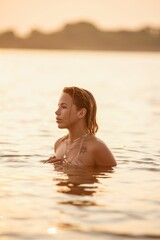 Wall Mural - young brazilian woman with tattoos enjoying a serene swim at sunset