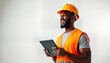 © miss irine - Cheerful black construction worker uses digital tablet. Man wears safety helmet, orange uniform. Smiling, looking happily at project on tablet. Studio shot on white background. Modern worker in
