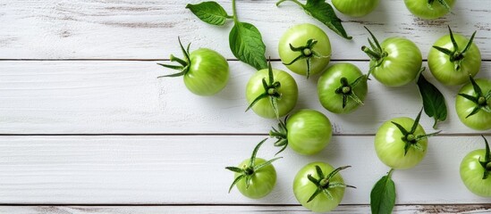 Fototapete - Green unripe tomatoes on a white wooden surface Top view. with copy space image. Place for adding text or design