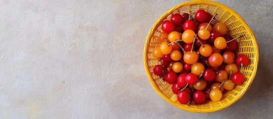 Fototapete - Top view of red and yellow cherry berries in a yellow basket on a light textured backdrop with copy space