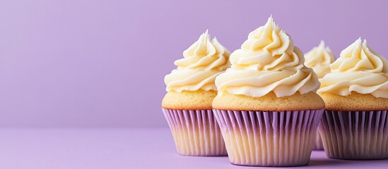 Poster - Cupcakes adorned with yellow cream on a violet pastel background with copy space perfect for a birthday or wedding greeting card