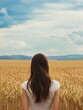© The 2R Artificiality - Brunette woman gazing thoughtfully into a vast golden wheat field under a dramatic blue sky, ideal for text overlay, portrait orientation.