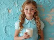 © The 2R Artificiality - Little girl with long curly hair holding a glass of milk indoors against a textured blue wall with ample empty space for text and copy.