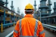 © miss irine - Worker in protective gear observes oil refinery equipment. Person in safety clothing stands near industrial machinery. Engineer focused on maintenance tasks at production plant. Pro industrial worker