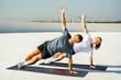 © muse studio - Fitness enthusiasts perform side planks on rooftops in sunny urban setting for a healthy lifestyle