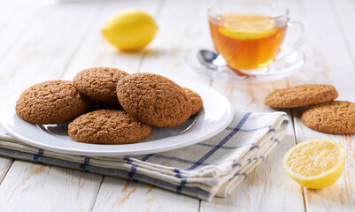 Wall Mural - Tasty oatmeal cookies and tea on a light kitchen table, selective focus.