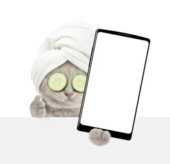 Leinwandbilder - Cute tiny kitten with towel on it head holds  big smartphone with white blank screen in it paw above blank white banner and shows thumbs up gesture. Empty space for text. isolated on white background