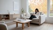 © Iona - A cozy minimalist living room featuring a light sofa, wooden coffee table, and an autumn view framed by large windows, creating a peaceful ambiance.