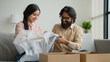 © Yuliia - Happy couple customers receive parcel look inside box Arabian Indian man and woman open delivery excited husband and wife shopping online unbox purchase unpacking present make internet order buy goods